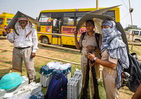 Polling officials with EVMs take cover amid intense heatwave conditions.